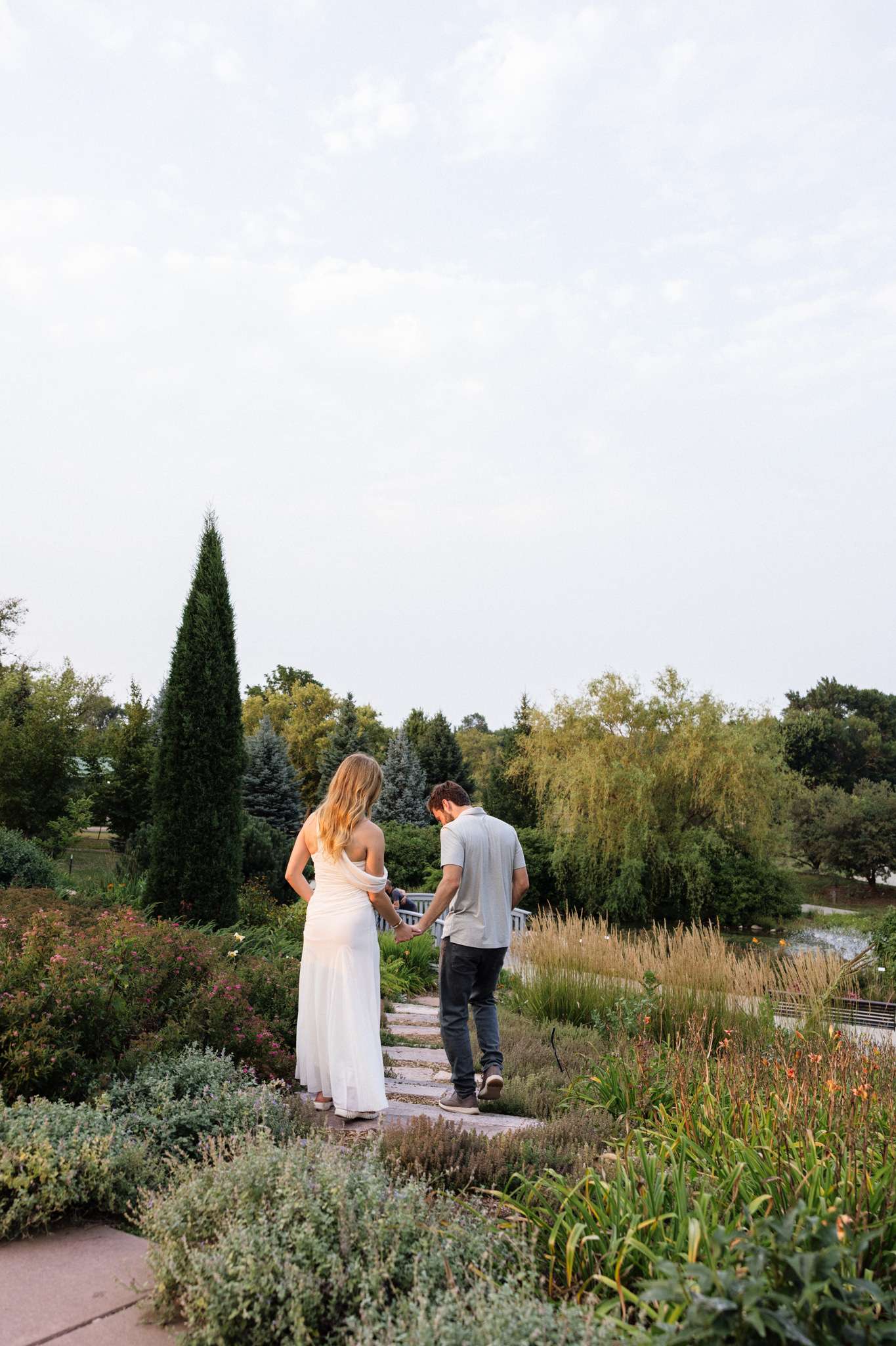 Cari and Trace walking hand in hand through the gardens at Mary Jo Wegner Arboretum during their Sioux Falls engagement session